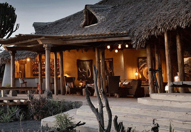 ol-donyo-lodge-chyulu-hills-main-lounge-in-the-chyulu-hills-features-a-grand-stone-fireplace-a-small-library-an-inviting-open-bar-and-an-expansive-verandah Ol Donyo Lodge Chyulu Hills Kenya Safari
