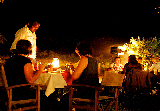 voyager-ziwani-camp-tsavo-west-national-park-evening-candlelit-tables-are-arranged-on-the-lawn-so-that-guests-can-dine-out-under-the-night-sky-beside-a-roaring-campfire Voyager Ziwani Camp Tsavo West National Park